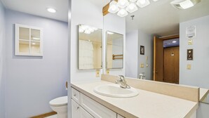 Un baño con un lavabo blanco, espejos dobles y una puerta de madera.