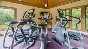 A gym with treadmills and ellipticals, large windows, and a wooden ceiling. - Charming Highridge Condo F2: Access to Pool, Hot Tub, and More! (Killington)