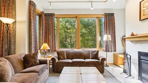 A cozy living room with a brown leather sofa, a wooden coffee table, and a fireplace. - Charming Highridge Condo F2: Access to Pool, Hot Tub, and More! (Killington)