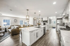 A spacious kitchen with white cabinetry, a central island, and stainless steel appliances.