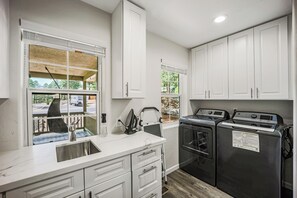 A kitchen with white cabinets, a stainless steel sink, and a built-in oven. - Modern Beauty, Gorgeous Forest View, Hot Tub, A/C, Game Room, Close to Downtown! (Flagstaff)