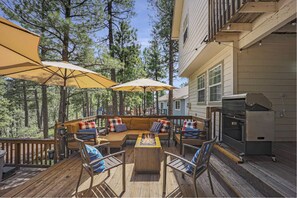 A deck with outdoor seating, a fire pit, and a grill.
