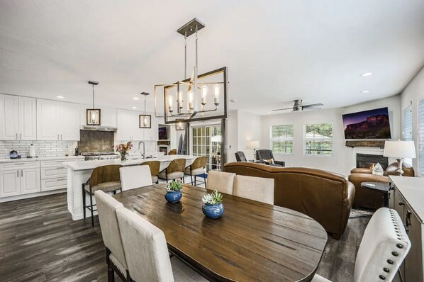 A spacious kitchen with white cabinets, a central island, and pendant lighting.