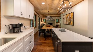 Una cocina moderna con armarios blancos, techo de madera y una isla central con asientos.