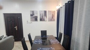 A dining area with a rectangular table, six chairs, and three wall-mounted artworks. - Apartment Vacation Rental Accra Adenta  (MARLEJOR, Adenta Municipality)