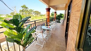 A balcony with a tiled floor, white chairs, and a table with a bottle. - Apartment Vacation Rental Accra Adenta  (MARLEJOR, Adenta Municipality)