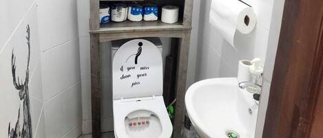 Une petite salle de bain avec des toilettes, un lavabo et un meuble de rangement.