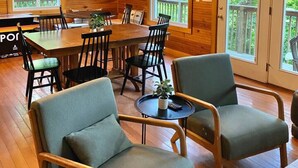 Interior de uma cabana de madeira com uma mesa de jantar, cadeiras e um candelabro.