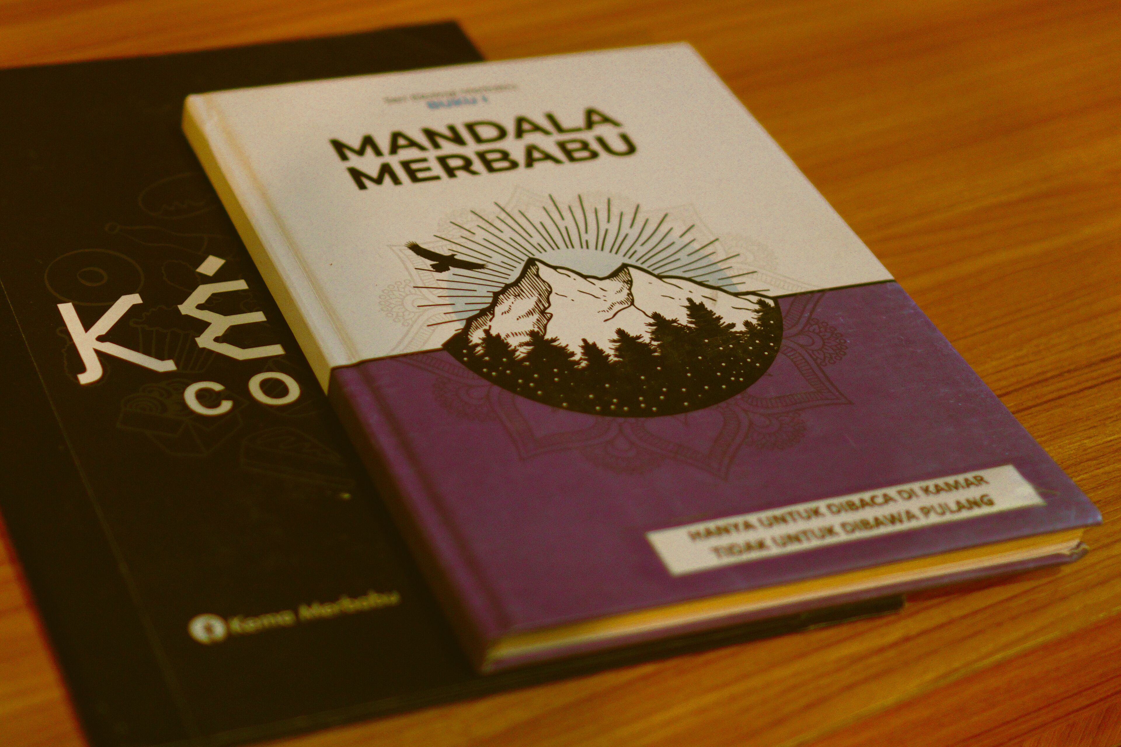 Two books titled 'Mandala Merbabu' and 'Ké Co' on a wooden surface.