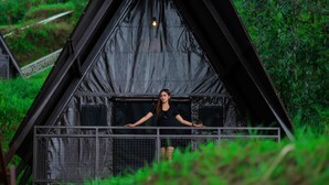 A person standing on a balcony of a black, triangular-roofed structure surrounded by greenery. - KEMA Merbabu powered by Cocotel (Ampel)