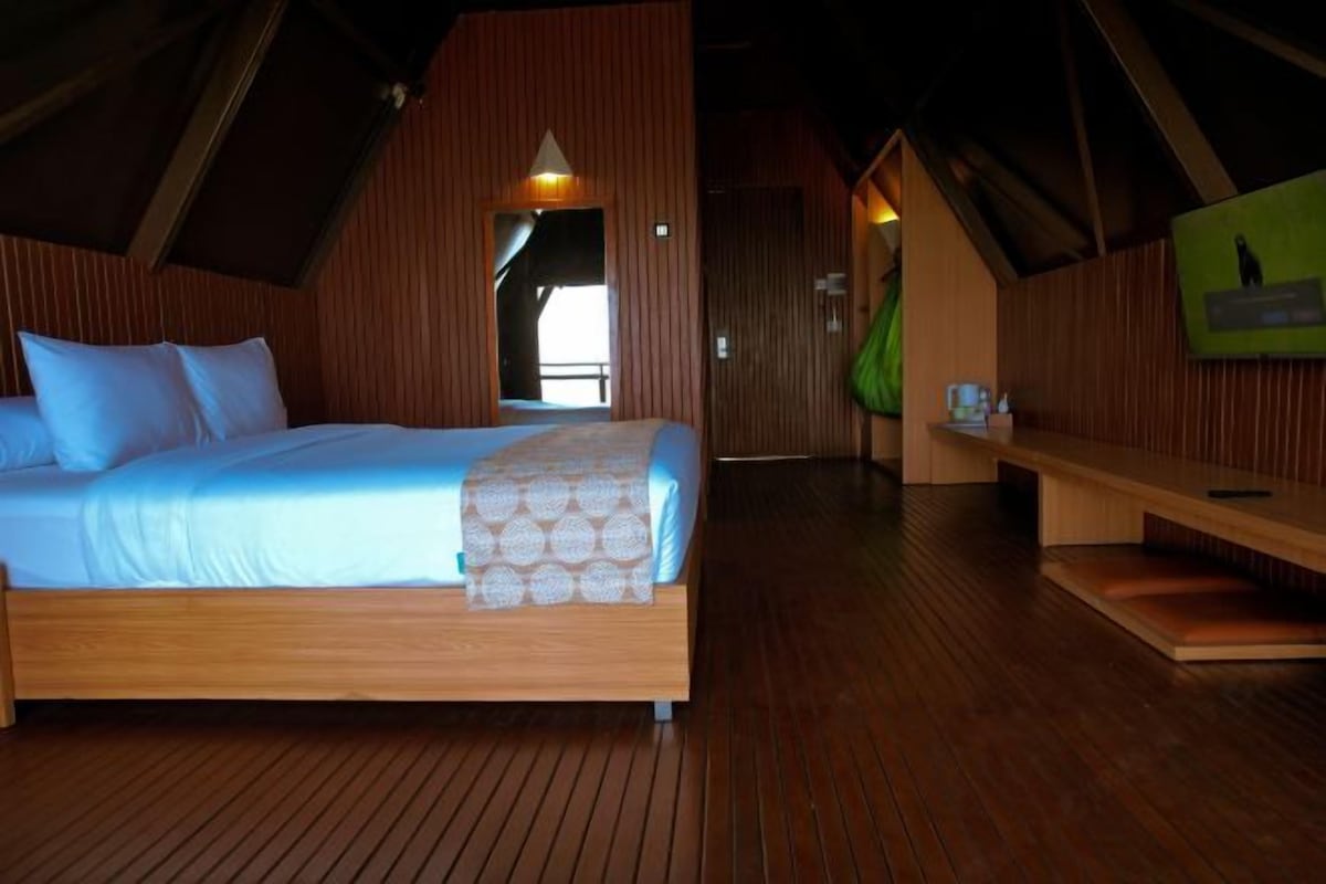 Un dormitorio con una cama de madera, un banco y un televisor en la pared.