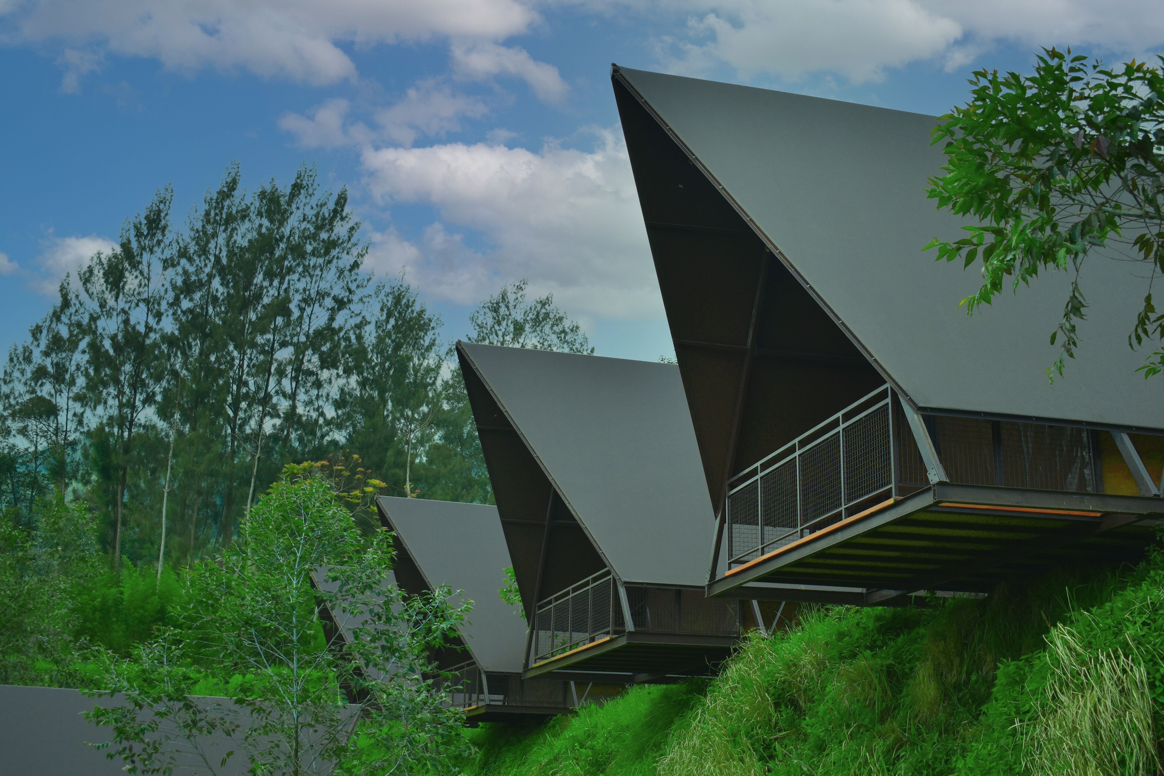 A modern building with geometric architecture, surrounded by lush greenery.