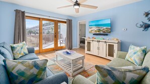 Un salon équipé d’un ventilateur de plafond, d’un téléviseur à écran plat, d’un canapé et d’une table basse.