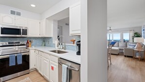 A modern kitchen with white cabinets, stainless steel appliances, and a view to the living area.