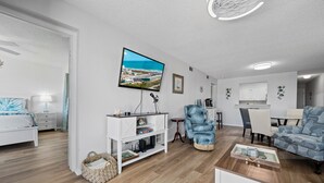 Ein modernes Wohnzimmer mit Flachbildfernseher, einer Couch, einem Couchtisch und einem Essbereich.