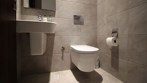 Un baño moderno con un lavamanos blanco, inodoro y espejo sobre el lavamanos.