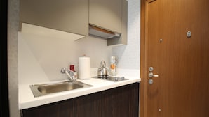 Una cocina moderna con un lavamanos de acero inoxidable, una tetera y una cafetera sobre la encimera.