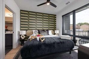 Quarto moderno com uma cama grande, ventilador de teto, vista pela janela e parede com padrão verde.