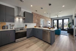 A modern kitchen with grey cabinets, stainless steel appliances, and a large island. - Halcyon-Odyssey-Walk to Restaurants & bars! (Nashville)