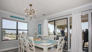 Ruokailutila, jossa on pöytä ja tuolit, kattokruunu, näkymä ulos ja kyltti, jossa lukee: ”A DRINK BREEZE PALM TREES”.