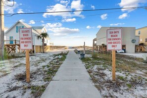 Ein Weg, der zu Strandhäusern führt, mit Schildern, auf denen 'Sea Oats Beach für Eigentümer und Gäste' steht.