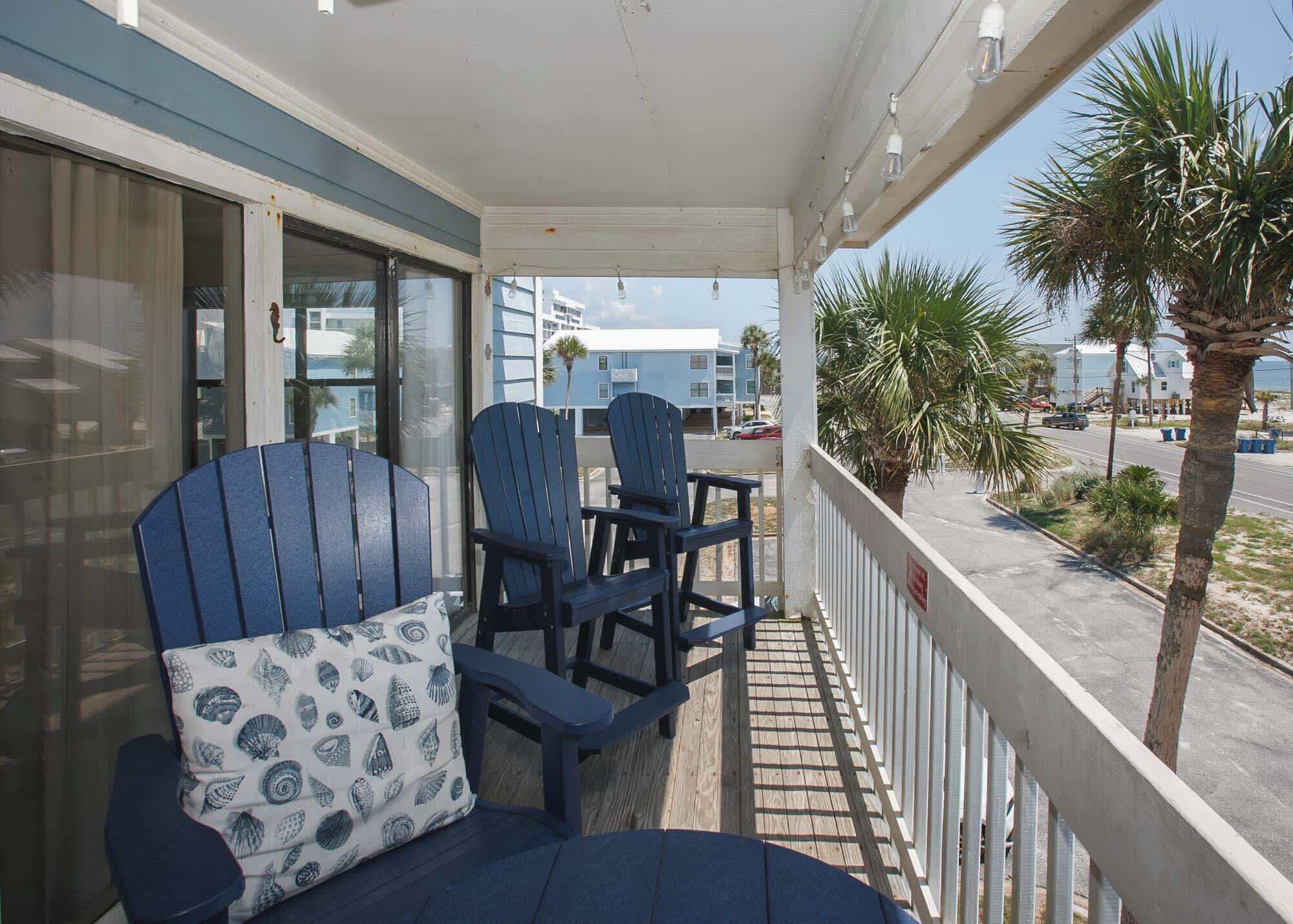 A balcony with two Adirondack chairs and a patterned cushion.