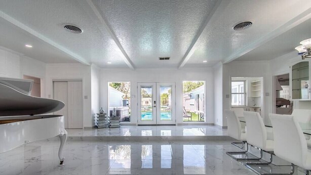 A spacious, modern interior with a piano, a pool view, and a dining area. - Ocean View + Poolside Opulence Tennis (Corpus Christi)