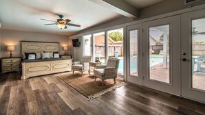 A bedroom with a large bed, a ceiling fan, and a view of a backyard with a pool. - Sail Away! Your Coastal Pool Oasis Awaits (Corpus Christi)