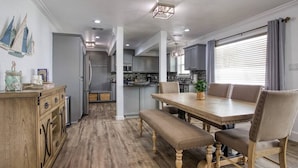 A dining area with a wooden table, cushioned chairs, and a bench. - Your Seaside Sanctuary on Ocean Drive Awaits (Corpus Christi)