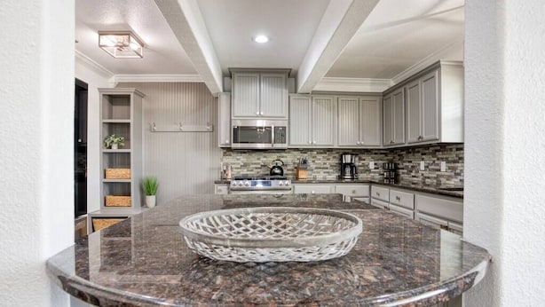 A modern kitchen with white cabinets, a granite countertop, and a microwave. - Your Seaside Sanctuary on Ocean Drive Awaits (Corpus Christi)