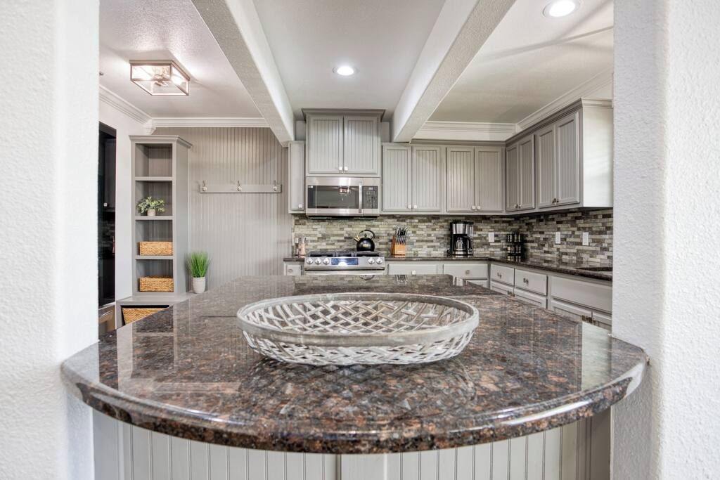 A modern kitchen with white cabinets, a granite countertop, and a microwave.