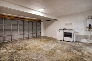 A garage with a concrete floor, a metal garage door, and a washing machine.