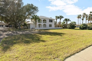 A two-story house with a front lawn, palm trees, and a clear sky. - Corpus Christi Gem (Corpus Christi)