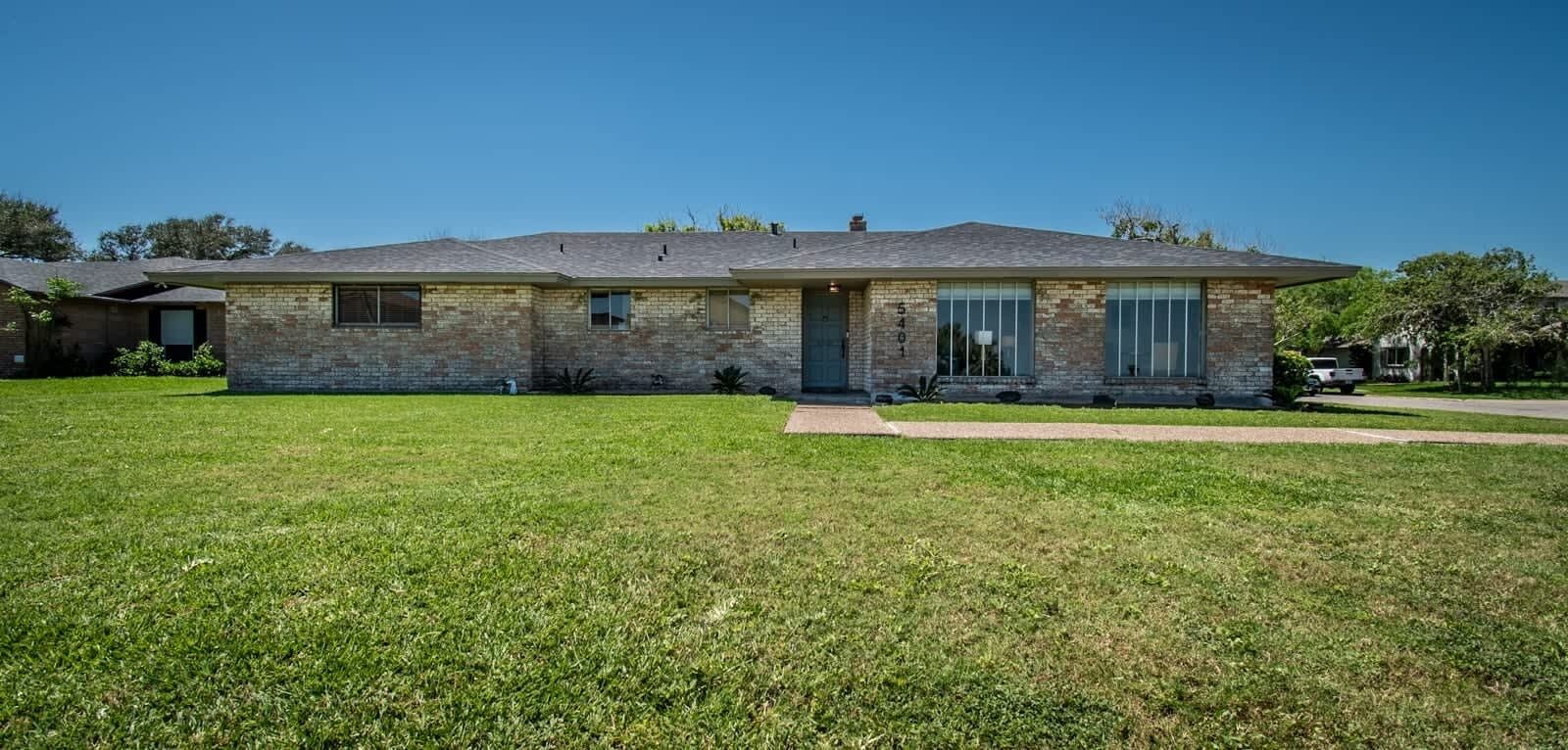 A single-story house with a brick exterior, a front porch, and a well-maintained lawn.