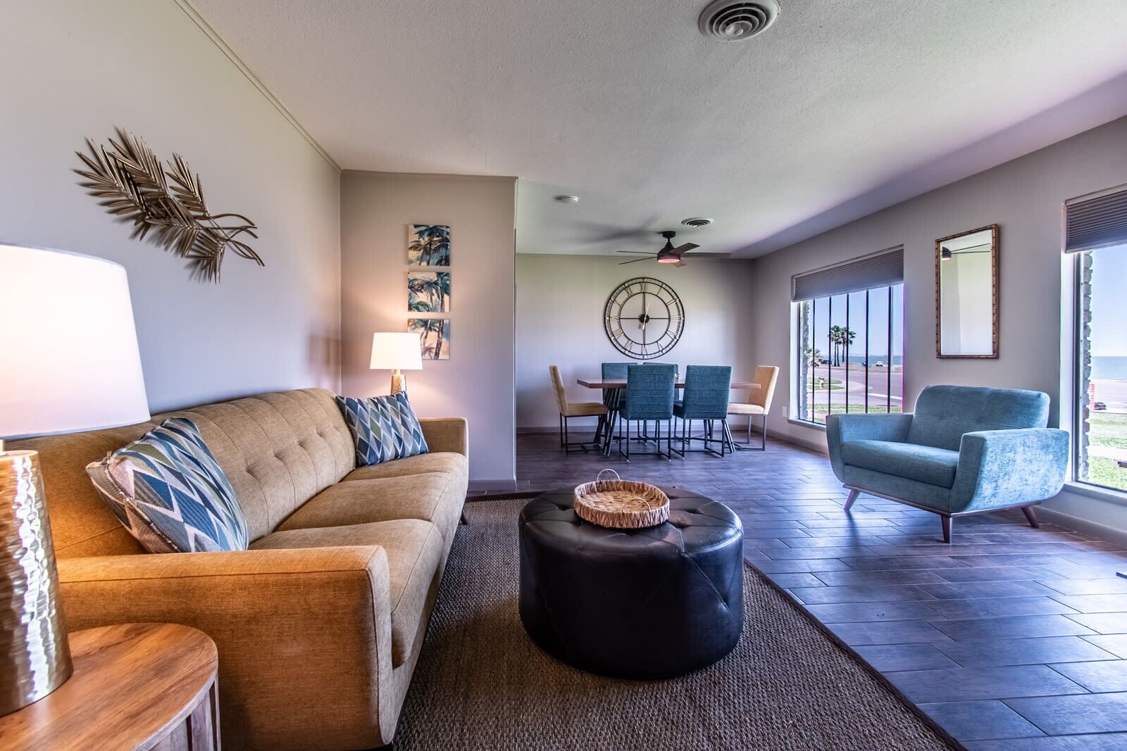 A spacious living room with a sofa, ottoman, and a dining area with chairs and a table.