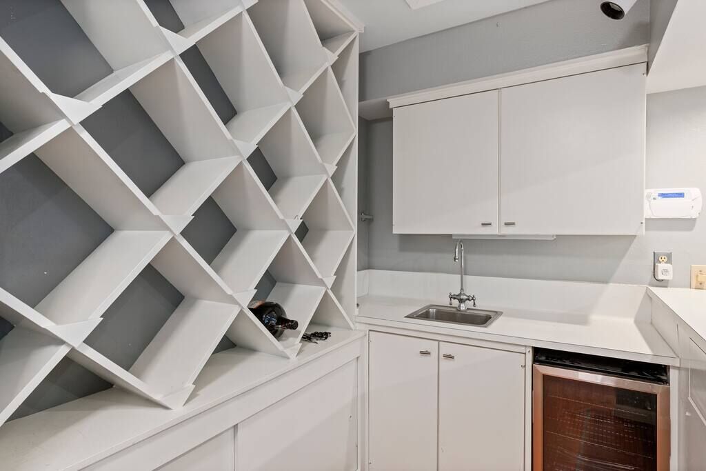 Een moderne keuken met witte kasten, een ingebouwde wijnrek en een vaatwasser.