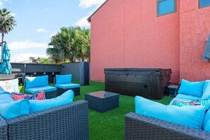 A backyard with outdoor furniture, a hot tub, and a red building. - Ocean Drive Oasis w Hot Tub Awaits (Corpus Christi)