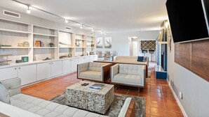 A spacious living area with a sofa, two armchairs, a coffee table, and built-in shelving. - Ocean Drive Oasis w Hot Tub Awaits (Corpus Christi)