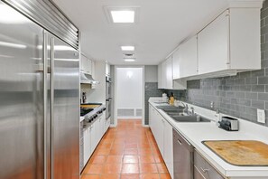 A modern kitchen with stainless steel appliances, white cabinets, and a tiled backsplash. - Ocean Drive Oasis w Hot Tub Awaits (Corpus Christi)
