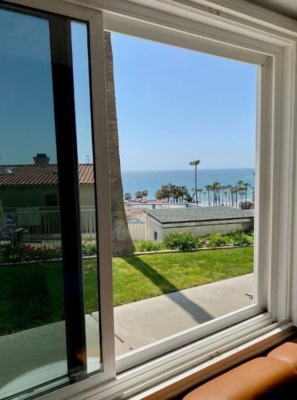 A view from a window with a clear sky and a distant ocean.