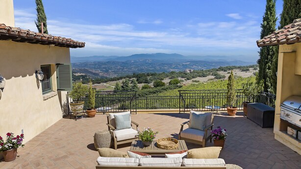 Un patio con mobiliario exterior, una parrilla y vistas al campo.