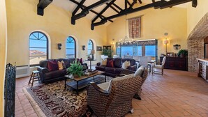 Un salón amplio con techo alto, ventanas grandes y chimenea.