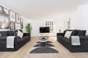A modern living room with two dark sofas, a coffee table, and a flat-screen TV.