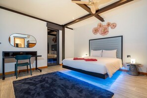Een moderne slaapkamer met een bed, bureau, stoel en een grote spiegel.