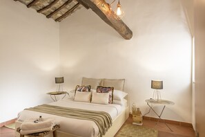 Una camera da letto con un letto, comodini, una lampada e un trave in legno al soffitto.