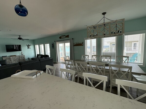 Uma sala de estar ampla com uma mesa de jantar e cadeiras, um sofá e um ventilador de teto.