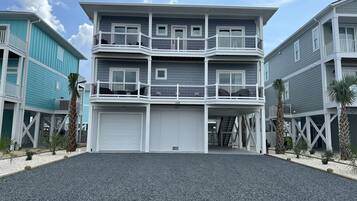 Un immeuble résidentiel à plusieurs étages, doté de balcons, d’un garage et d’une allée gravillonnée.