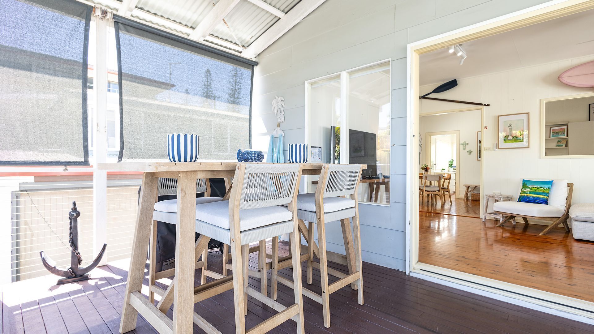 Un comedor con una mesa y sillas de madera, televisor y vistas al exterior.