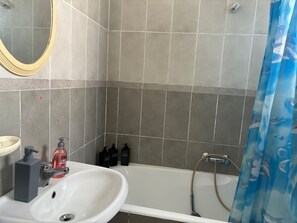 A bathroom with a white sink, a mirror, and a bathtub.