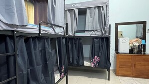 Een slaapzaal met stapelbedden, een spiegel, een dressoir en een kleine speaker.